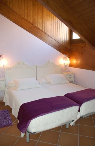 Dormitorio abuhardillado con dos camas en Casa Rojanda