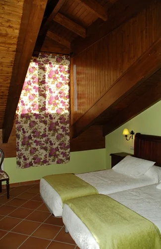 Habitación abuhardillada con textiles verdes en Casa Rojanda